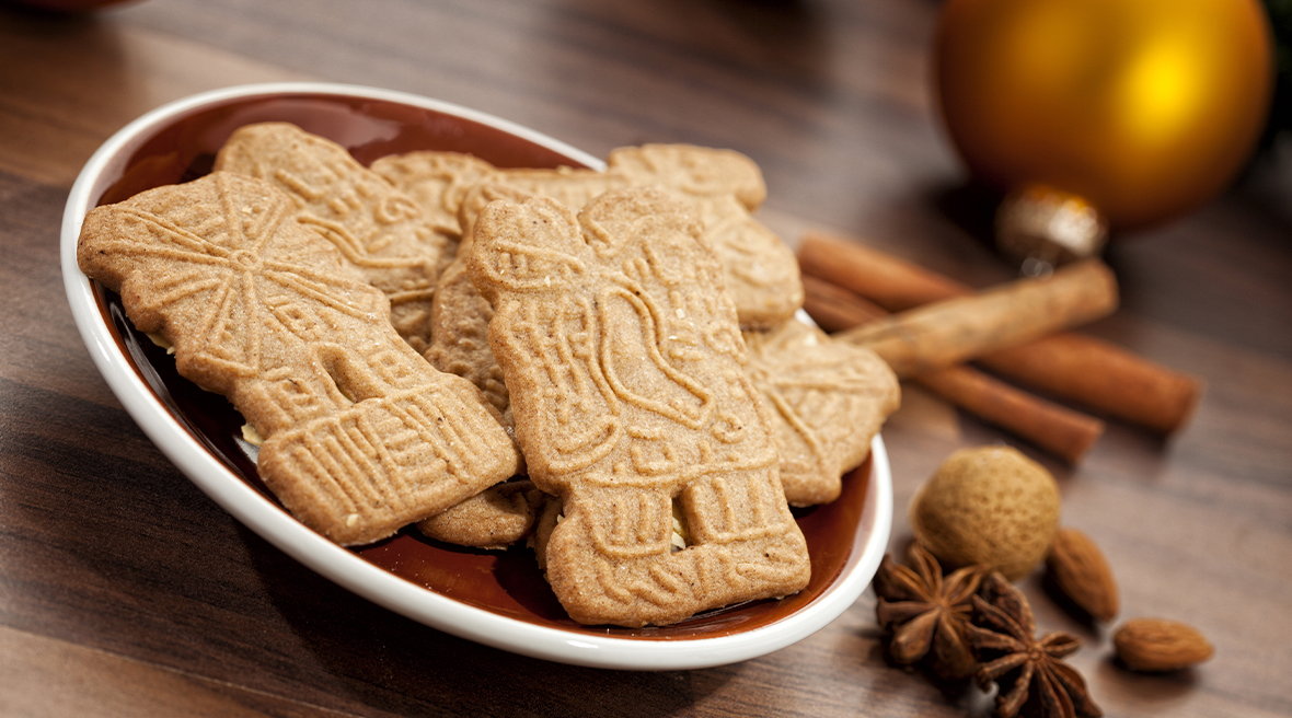 plate of patterned biscuits with cinnamon sticks and spices next to them